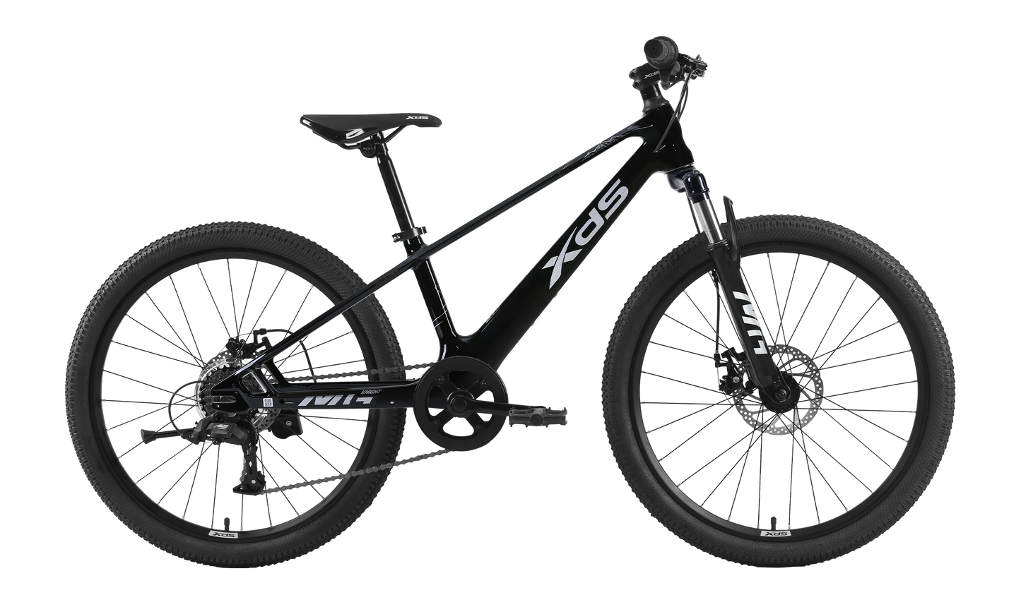 A side-view studio shot of a black XDS 20-inch children's mountain bike with a matte black frame, white XDS branding, front suspension fork, mechanical disc brakes, and rugged off-road tires against a dark, transparent background.